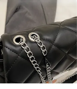 Detail of silver metal chain and quilted black leather texture on stylish handbag