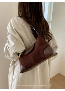 Minimalist dark brown suede bag back view with white pearl charm on model in cream coat