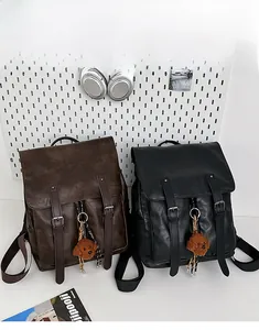 Dettaglio di zaini in pelle PU in nero e marrone scuro con ciondoli a forma di orso