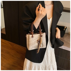 Detail of grey bucket bag with brown tassels and vintage metal ring hardware