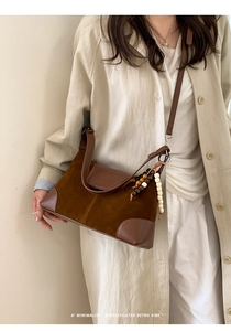 Close-up of minimalist brown suede and leather crossbody bag with beaded charm detail