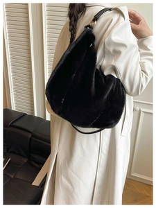 Détail du sac hobo en fausse fourrure noire avec bandoulière sur un manteau blanc