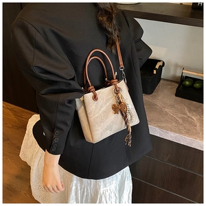 Close-up of a marble-textured bucket bag with pearl tassel detail on a fashion model