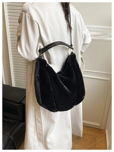 Détail d'un grand sac cabas en fausse fourrure noire avec anses en cuir et design minimaliste