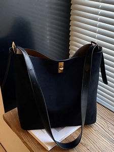 Chic black matte bucket bag with gold twist lock on a sunlit wooden surface