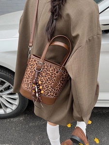 Fashionable leopard print bucket bag with brown leather trim and beaded tassel accessory