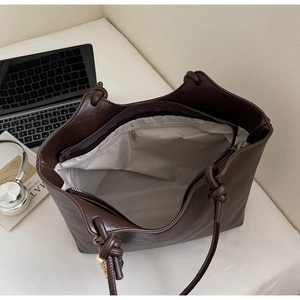 Top view of large brown tote bag interior with zipper pockets and stylish knotted straps
