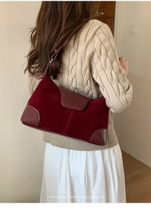 Model wearing dark red suede crossbody bag with premium stitching details