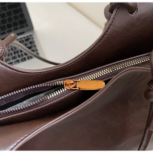 Detail of golden metal zipper and matte dark brown leather on the large tote bag