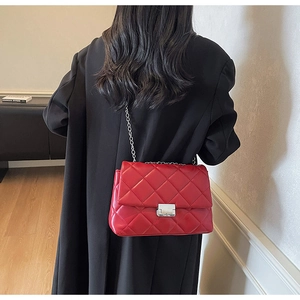 Detail of red quilted leather crossbody bag with silver chain strap and metal clasp