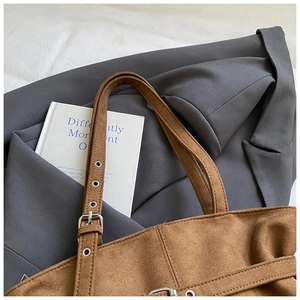 Detailed view of brown suede tote bag with adjustable silver buckle on a blazer