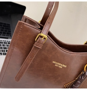 Close-up of vintage brown tote bag with gold lettering and adjustable buckle strap