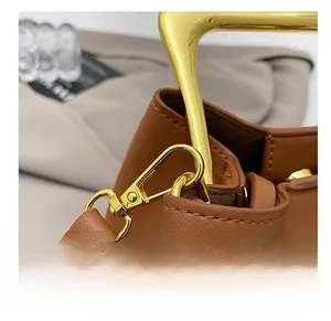 Detailed close-up of premium golden metal hardware hook on a brown leather bucket bag