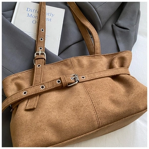Detailed close-up of brown suede tote bag with silver metal eyelets and buckle accents