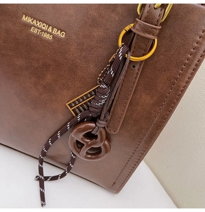 Detail of dark brown vintage tote with bow pendant and textured faux leather finish