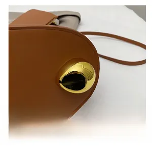 Close-up of brown leather bucket bag bottom with polished gold metal feet for protection