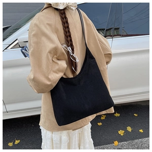 Detail of minimalist black matte tote bag with wide strap on model back view