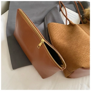 Detail view of brown faux leather pouch with gold zipper and textured woven tote bag