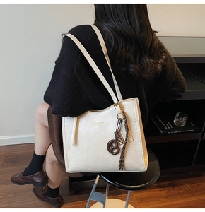 Detail of cream underarm bag showing the embossed logo and trendy pretzel charm detail