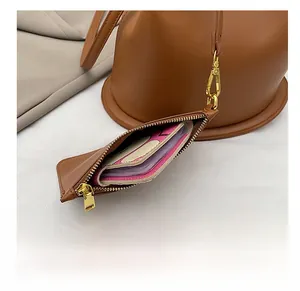 Close-up of brown leather pouch with gold zipper and pink lining on a bucket bag