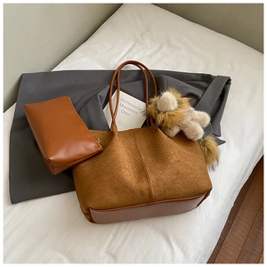 Detail shot of large brown woven tote bag set with matching zipper pouch and lion charm
