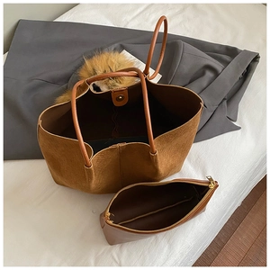 Detailed view of woven brown tote bag with matching inner pouch on minimalist background