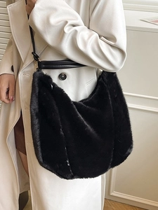 Sac hobo noir en fausse fourrure pour femme porté avec un trench-coat élégant