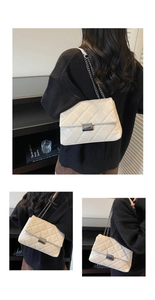 Detail of white quilted crossbody bag featuring silver chain strap and metal lock closure
