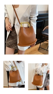Close-up of brown leather bucket bag featuring unique round base and golden U-shaped handle