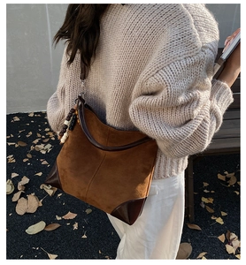 Brown suede tote bag with leather stitching and bead charm shown on model in autumn park