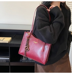 Detail of burgundy leather tote bag with brand logo, twist charm and side drawstrings