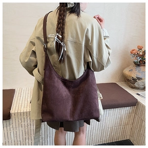 Detail of deep brown faux suede tote bag with adjustable shoulder strap and metal buckle