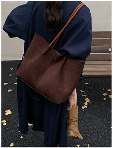 Detail of dark brown tote bag with woven texture on model in autumn park setting