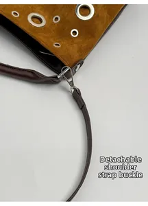 Detail of detachable shoulder strap with silver buckle on brown suede tote bag