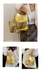 Detail of golden metallic bucket bag with matching mini pouch and stylish metal handle