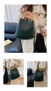 Detail of dark green bucket bag with gold U-shaped handle and crossbody strap