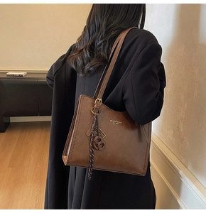 Detailed side view of brown matte leather tote bag with gold logo and vintage charm