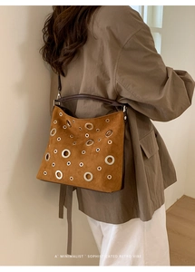 Brown suede underarm bag featuring silver metal eyelets and retro minimalist styling
