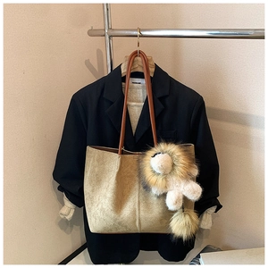 Close-up of khaki suede tote bag with brown straps and a lion plush pendant