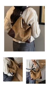 Close-up of brown suede tote bag with contrast leather corners and bead pendant
