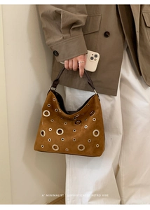 Detail of brown suede tote bag with decorative silver grommets and retro style