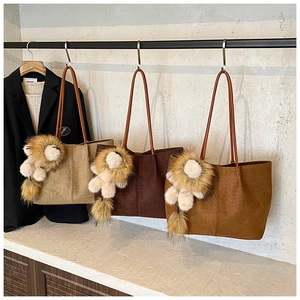 Detail of woven texture faux leather tote bag with a cute lion plush keychain accessory