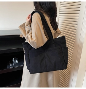 Détail du grand sac cabas en velours côtelé noir avec poches multiples porté à l'épaule