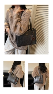 Detail of dark grey tote bag featuring gold lettering, textured leather, and woven charms