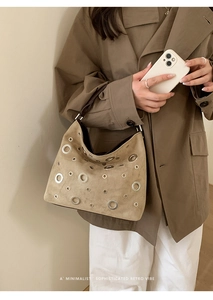 Detail view of light brown suede shoulder bag featuring stylish silver metal eyelet grommets