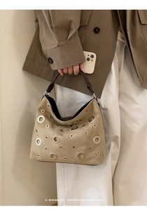 Detail showing the khaki suede leather handbag with silver grommets and dark handle strap