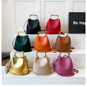 Close-up of bucket bags in eight colors featuring sleek gold metal handles and PU leather