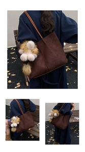Detail of woven brown suede tote bag with a cute lion plush charm in an outdoor park setting