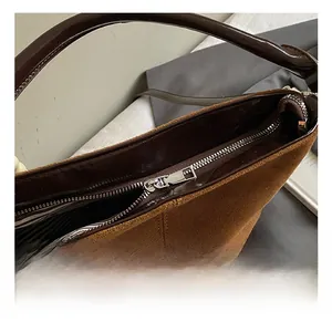 Detailed close-up of the silver metal zipper and striped lining on brown suede bag