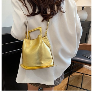 Detail view of champagne gold metallic bucket bag with unique square metal handle
